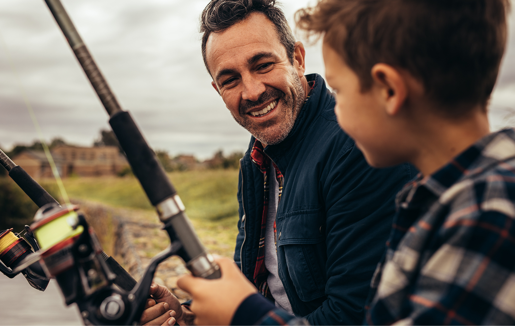 A father smiles at his happy child as they fish together.
